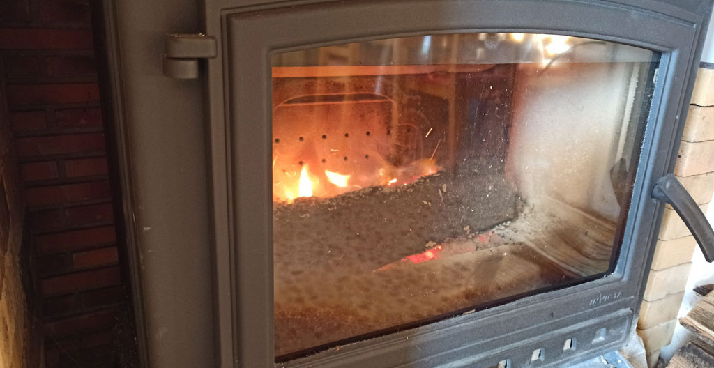 Une main se pose sur la surface d'un poêle éteint pour vérifier la chaleur résiduelle dans un salon lumineux